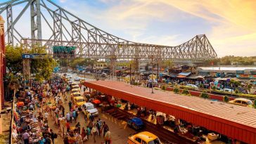 a group of people walking on a street with a bridge over it hawroh bridge