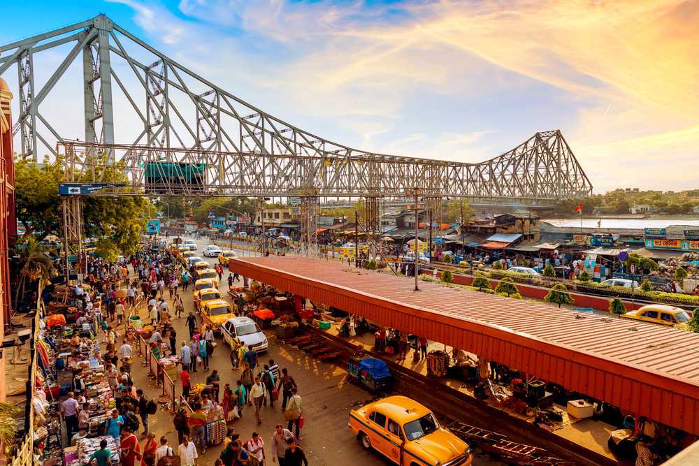 a group of people walking on a street with a bridge over it hawroh bridge
