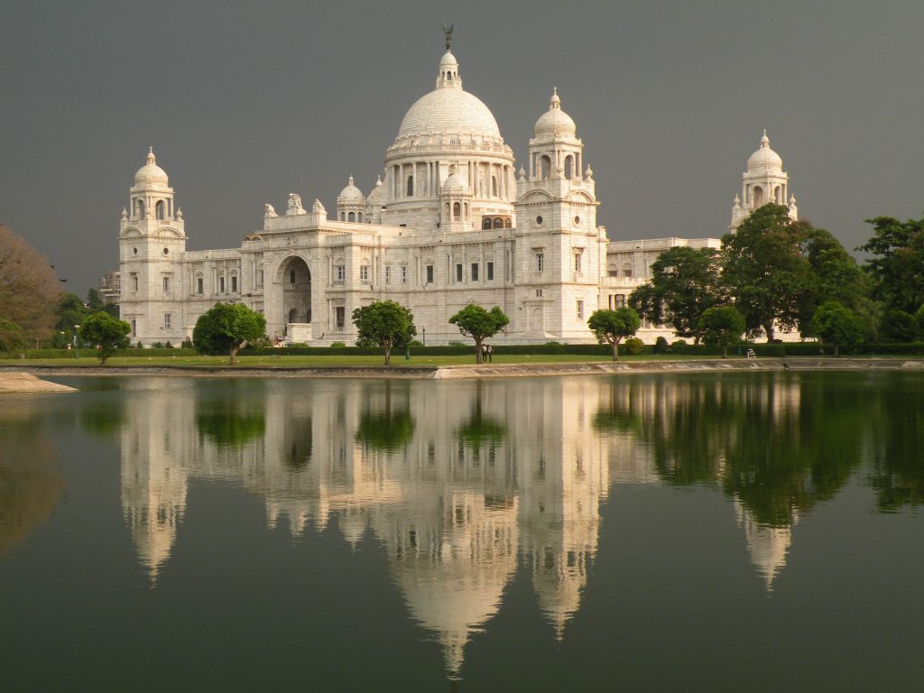 a large white building with a dome and trees in front of it with Victoria Memorial Hall in the background